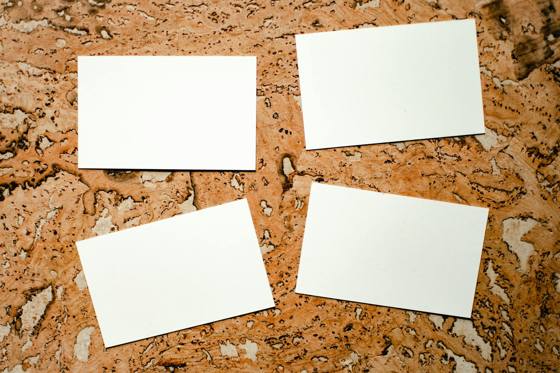 Four blank business cards on a textured marble background