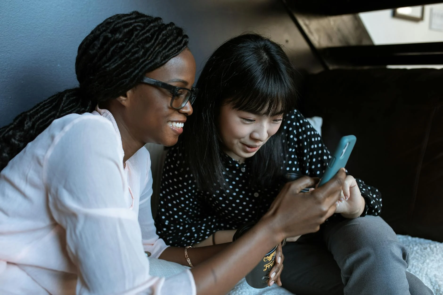 two women smiling and looking at a phone