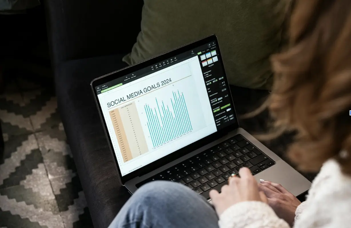 A woman reviewing 2024 social media goals on a laptop at home.